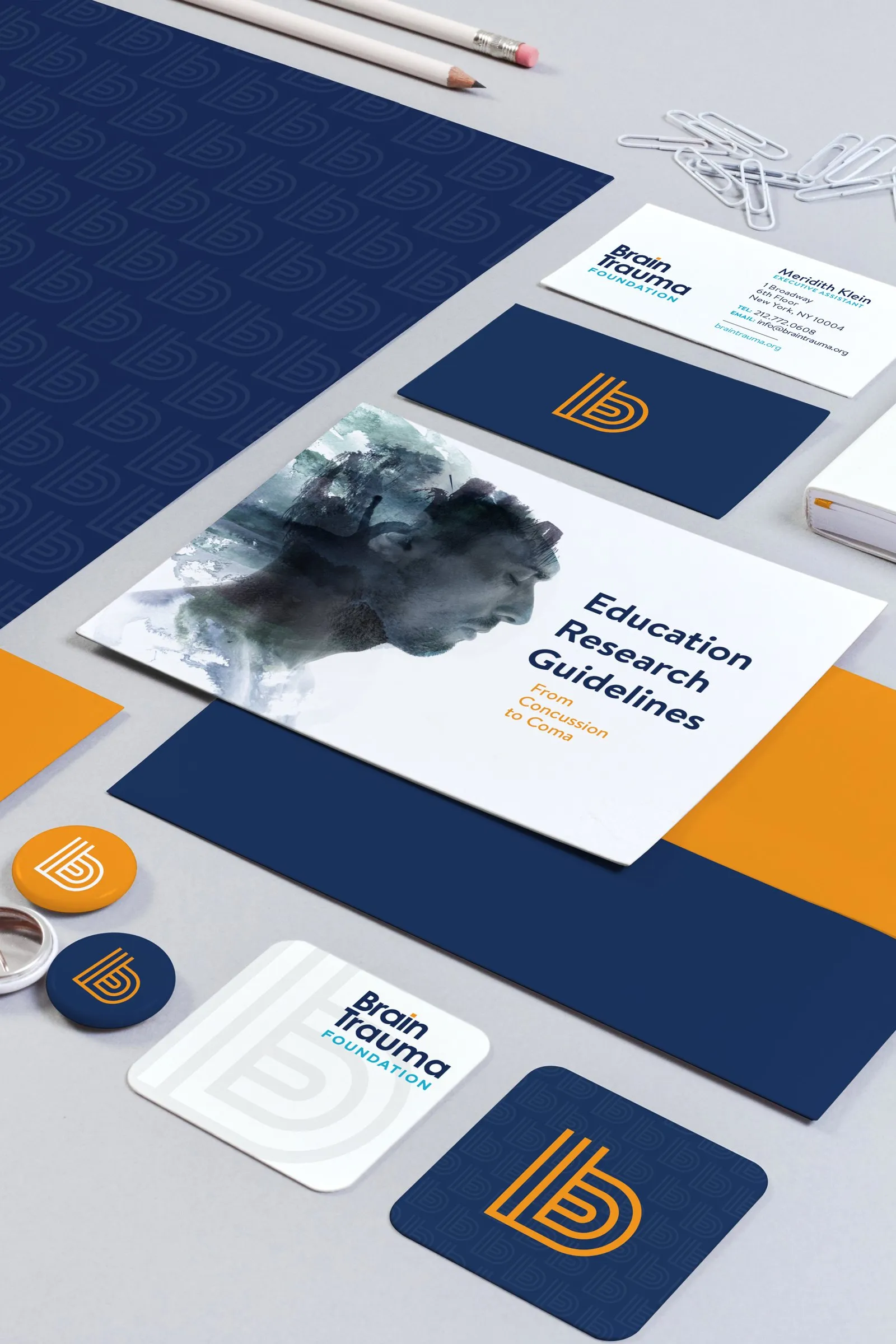 The stationery at an angle: a navy folder, a brochure with the signature image, cards and a sticker