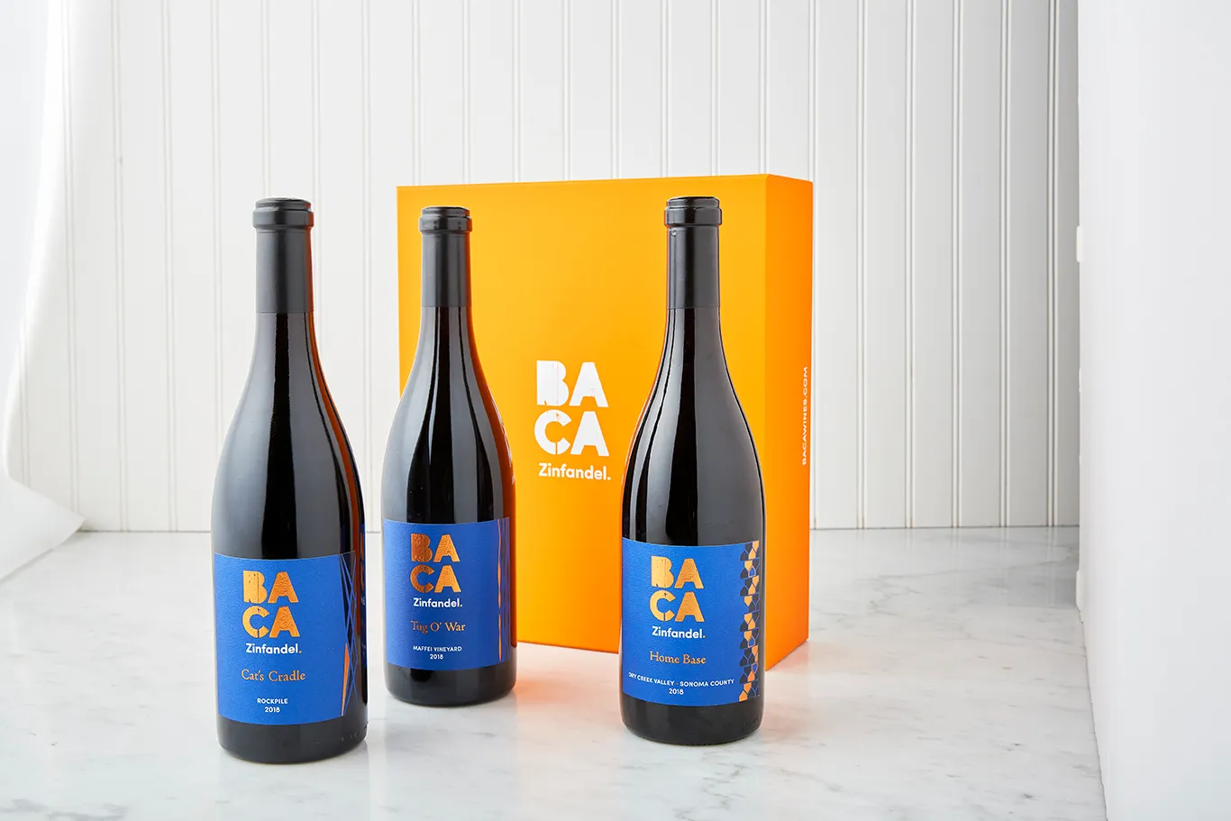 Three BACA bottles in front of an orange BACA gift box