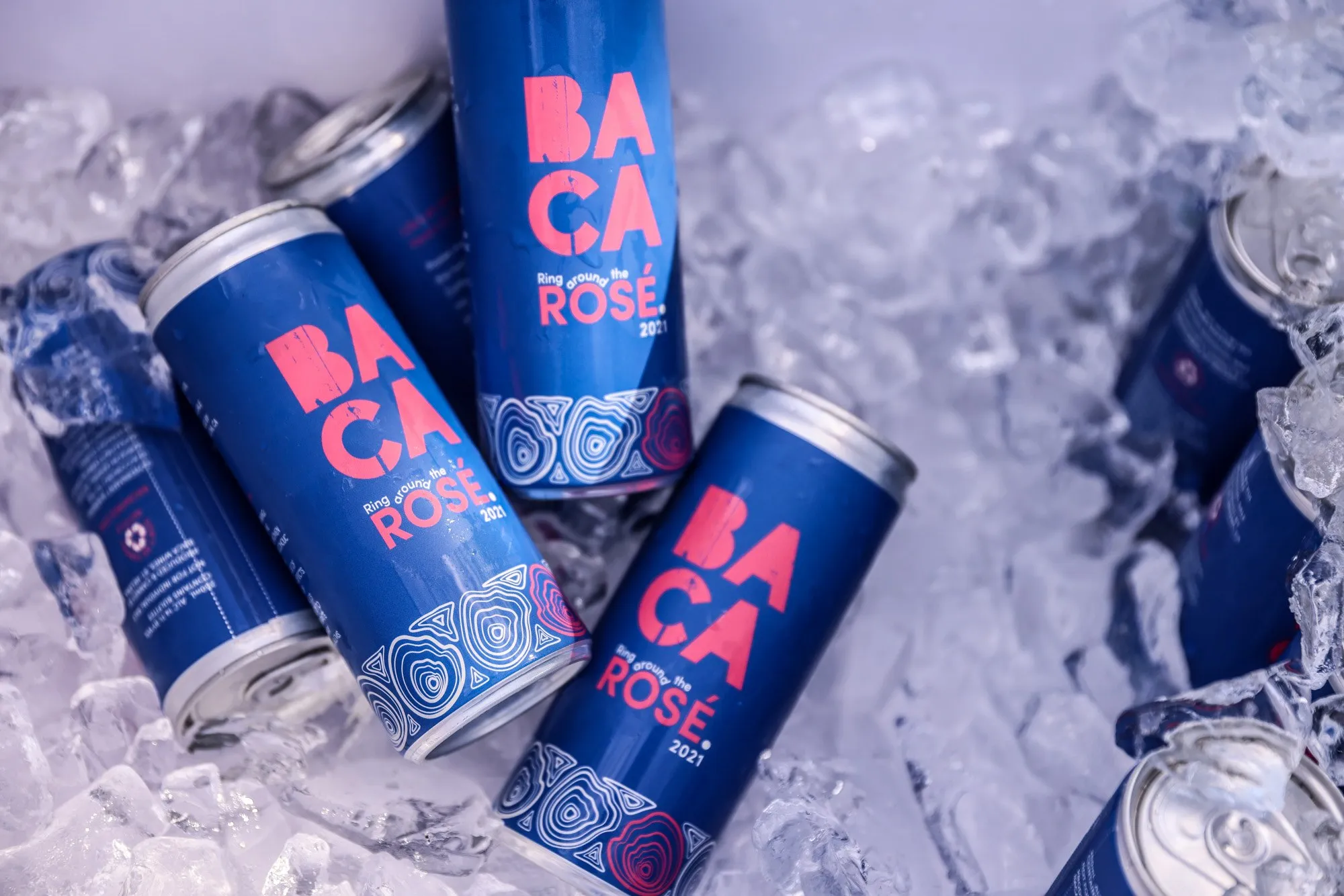 Cans of BACA Rosé on ice, the stacked mark in pink
