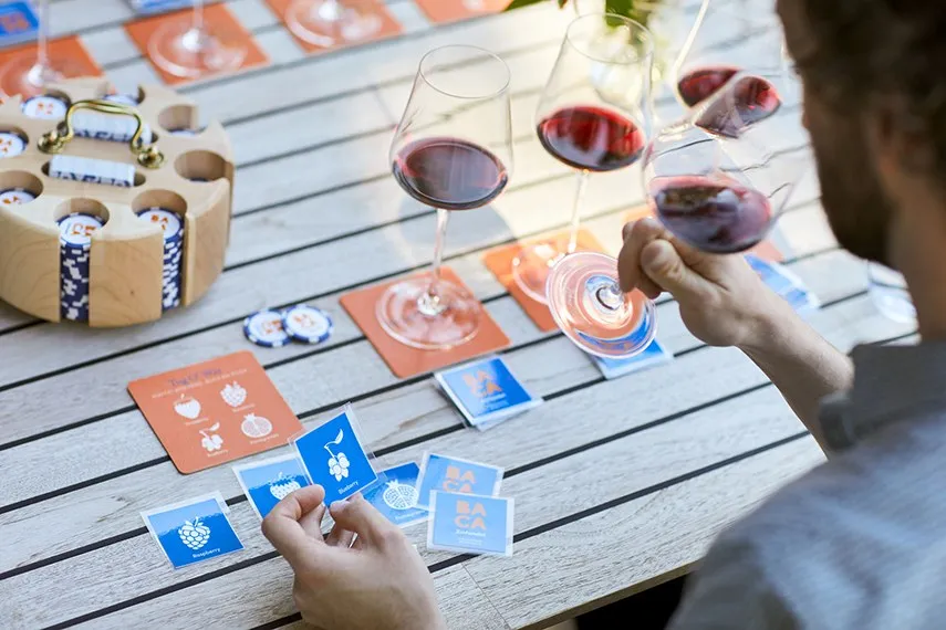 A game of BACA poker on a patio table, glasses of red all around